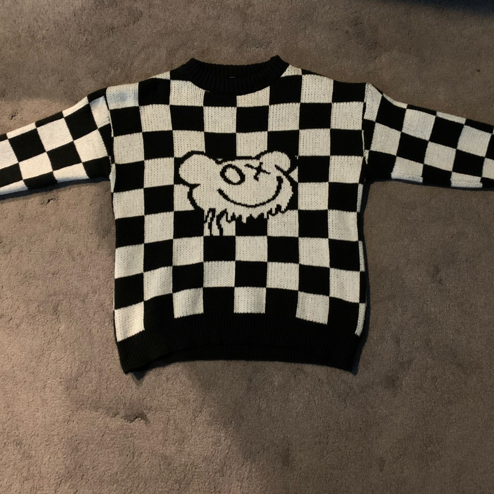 Long sleeved Black and white checkered sweater with a cute face in the middle